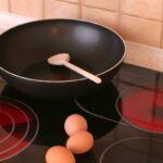 cooktop ligado de 4 bocas com uma frigideira e 3 ovos sobre o cooktop